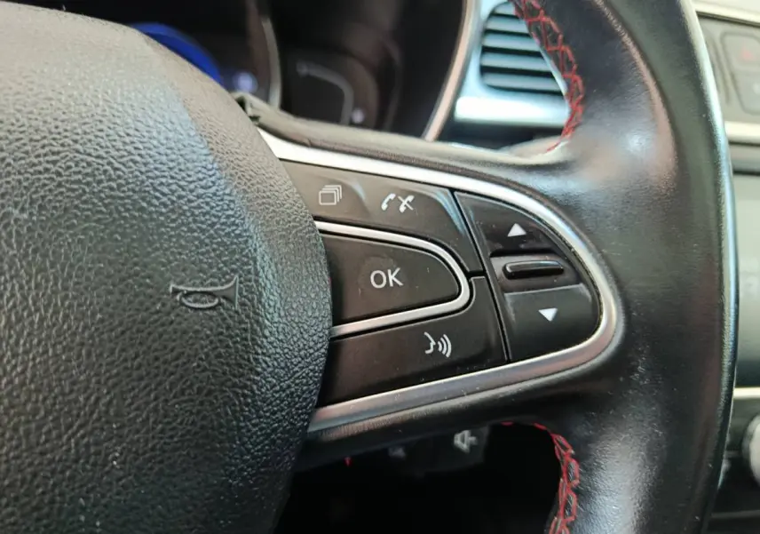 Gros plan sur le volant cuir noir avec surpiqûres rouges du Renault Kadjar, boutons de commande multifonctions visibles.