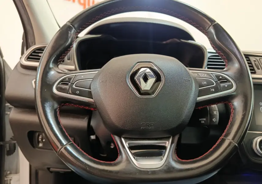 Gros plan sur le volant cuir noir avec surpiqûres rouges du Renault Kadjar Blanc, tableau de bord partiellement visible.