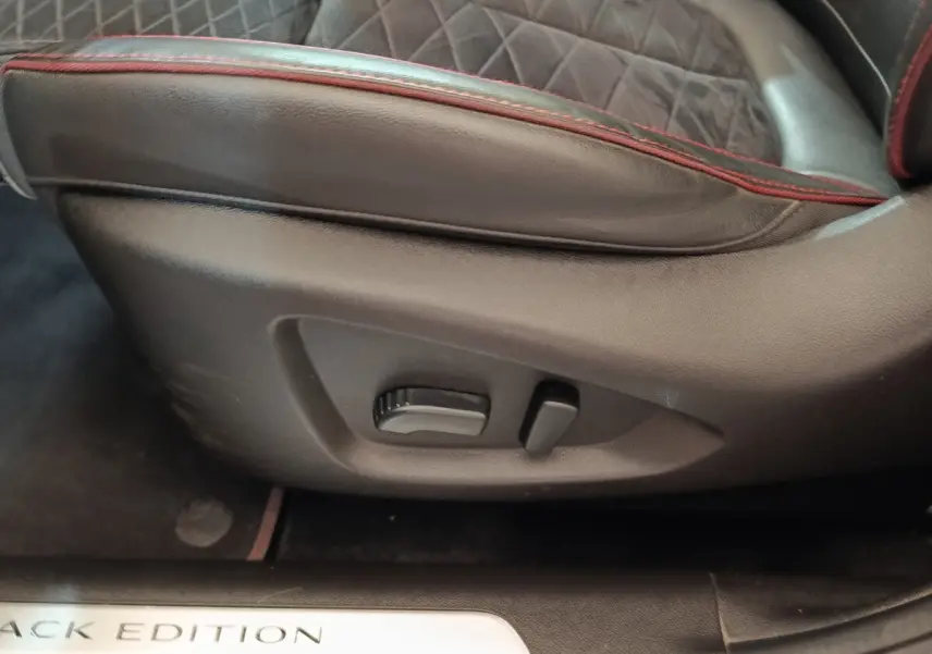 Gros plan sur la commande de réglage du siège cuir noir avec surpiqûres rouges du Renault Kadjar Black Edition.