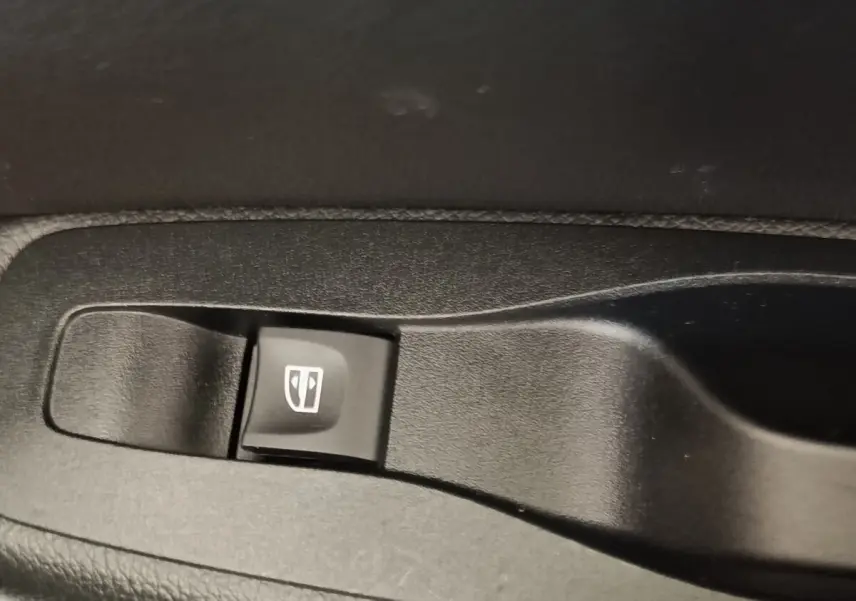 Gros plan sur bouton de commande de lève-vitre noir dans l’habitacle du Renault Kadjar blanc, version Black Edition.