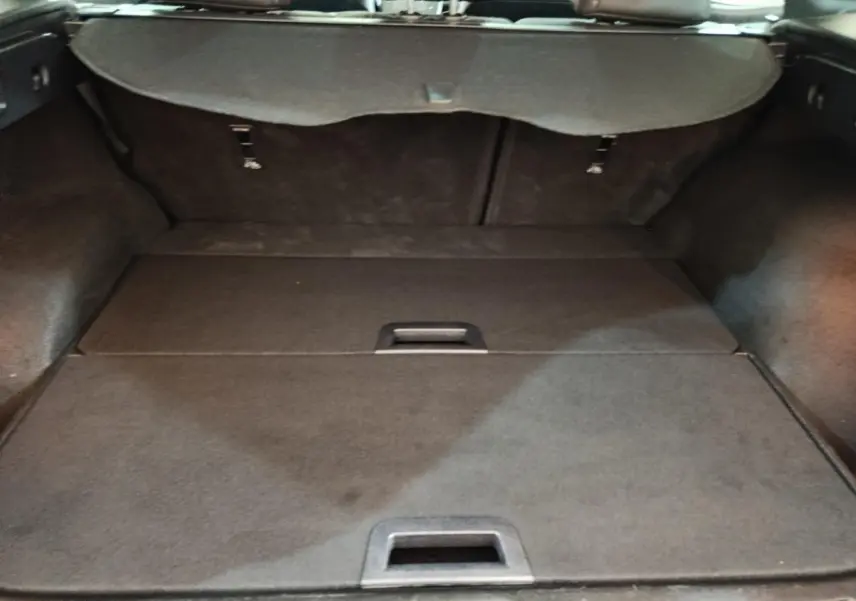 Coffre ouvert vu de l'intérieur d'un Renault Kadjar blanc, avec banquette arrière rabattue et cache-bagages en place.