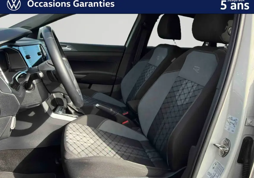 Vue intérieure côté conducteur du Volkswagen Taigo gris, mettant en valeur les sièges sport-confort à motifs géométriques et le volant multifonctions.