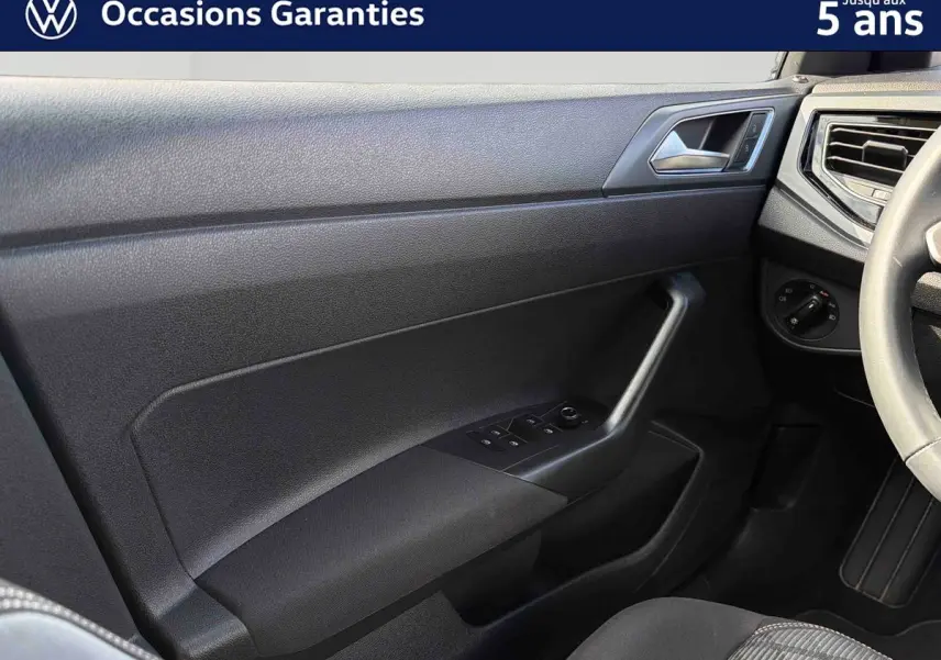 Intérieur côté conducteur du Volkswagen Taigo 2025, montrant la portière noire avec commandes des vitres et partie du volant cuir.