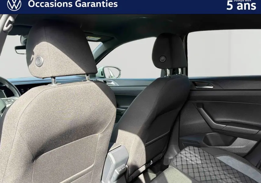 Vue intérieure arrière du Volkswagen Taigo 2025 montrant les sièges avant et la banquette arrière en tissu gris foncé.