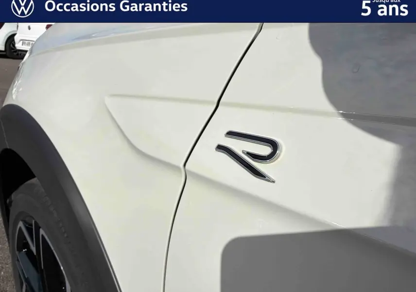 Détail de l'aile avant droite grise du Volkswagen Taigo avec logo R visible sur la carrosserie.