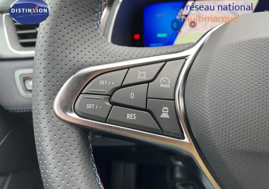 Gros plan sur les commandes à gauche du volant perforé avec surpiqûres bleues de la Renault Symbioz gris cassiopée.