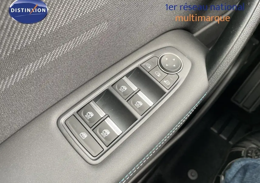 Gros plan sur les commandes de lève-vitres côté conducteur avec surpiqûres bleues dans l’habitacle noir du Renault Symbioz gris.