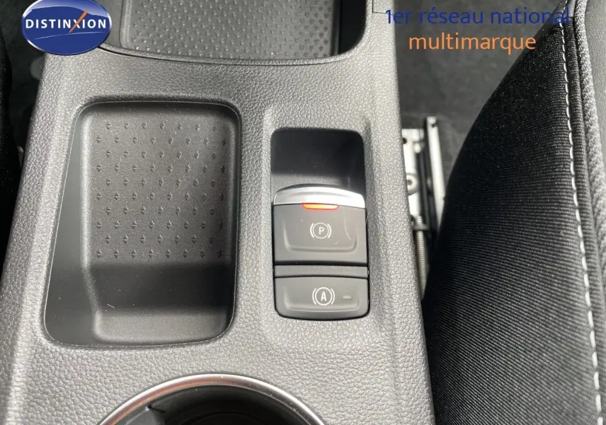 Gros plan sur la console centrale intérieure de la Renault Symbioz gris cassiopée, avec boutons de frein à main et arrêt auto.