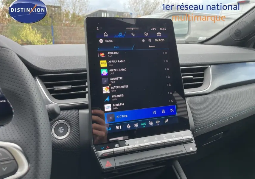 Vue intérieure centrée sur l'écran tactile vertical du tableau de bord de la Renault Symbioz gris cassiopée, avec volant partiel à gauche.