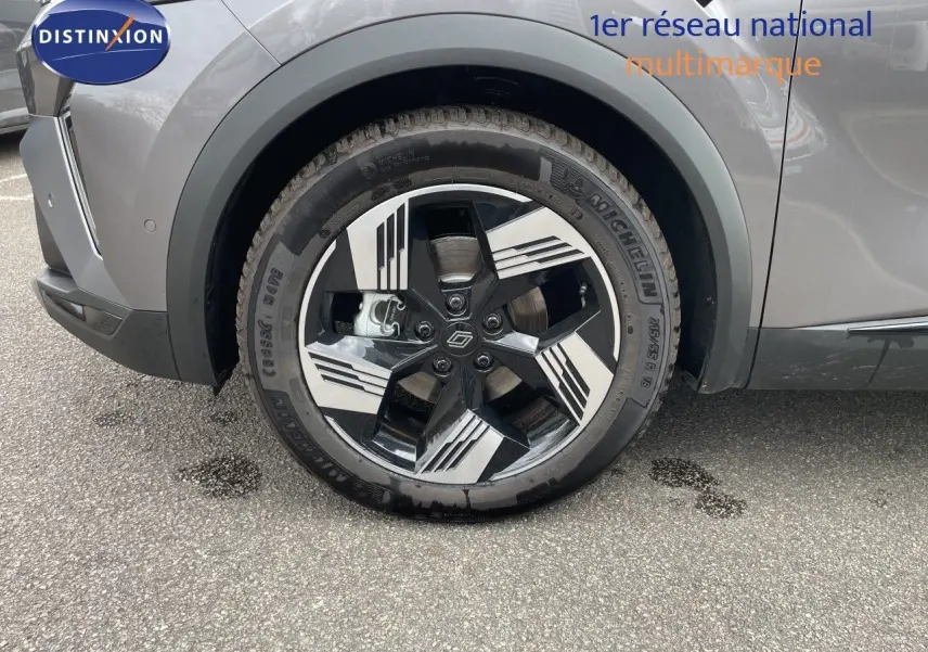 Gros plan sur la roue avant droite d'une Renault Symbioz gris cassiopée métal avec jante noire et argentée au design géométrique.