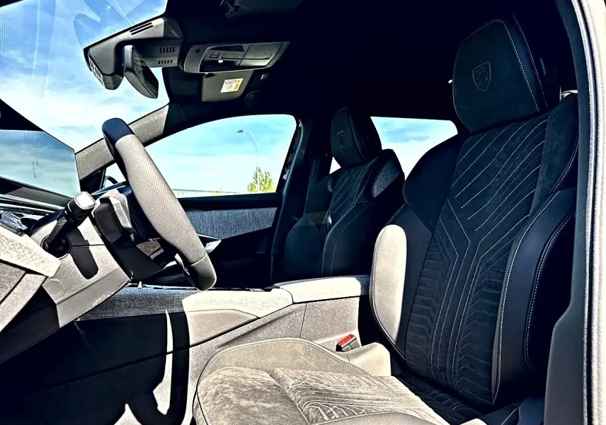 Vue intérieure côté conducteur du Peugeot 5008 Hybrid 145 GT e-dcs6 2025 avec sièges noirs en alcantara et logo Peugeot brodé.