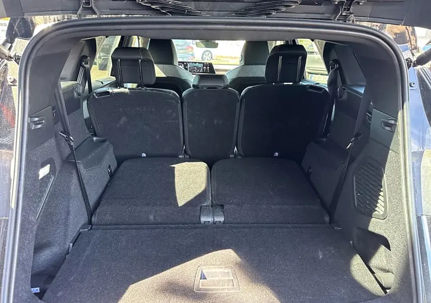 Vue depuis le coffre ouvert du Peugeot 5008 noir, montrant les sièges arrière partiellement rabattus et l'espace de chargement.