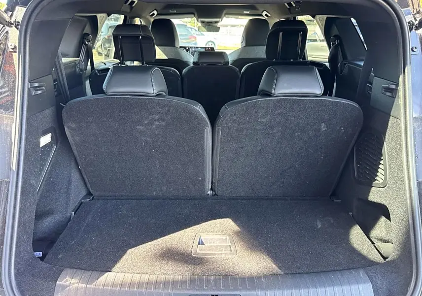 Vue arrière du coffre ouvert d’un Peugeot 5008 noir, montrant les sièges arrière relevés et l’habitacle intérieur.
