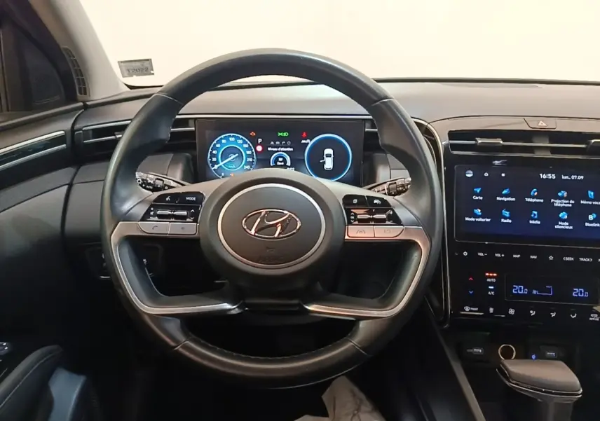 Vue intérieure centrée sur le volant noir du Hyundai Tucson 2021 avec tableau de bord digital et écran tactile.