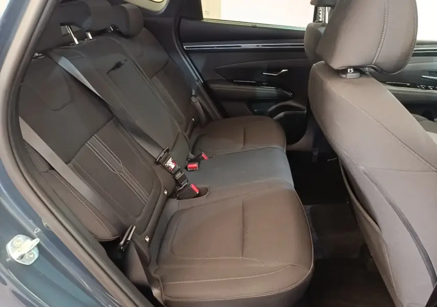 Vue intérieure côté gauche des sièges arrière noirs du Hyundai Tucson bleu, avec ceinture de sécurité visible.