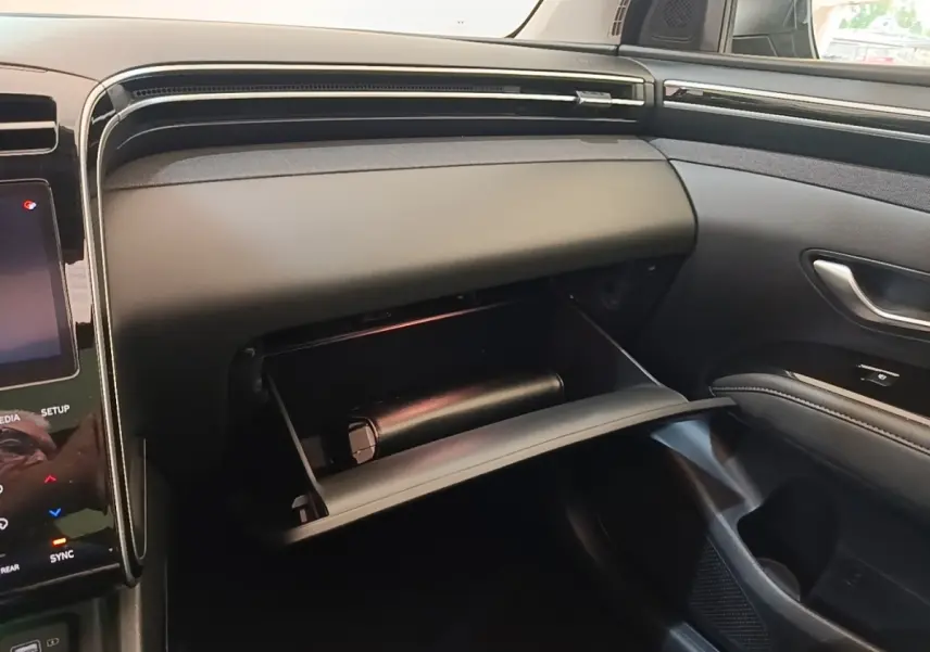 Intérieur du Hyundai Tucson bleu 2021, vue côté passager avec boîte à gants ouverte et tableau de bord noir.