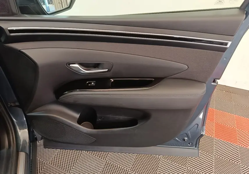 Vue intérieure de la porte avant gauche bleu foncé du Hyundai Tucson avec garniture noire et poignée argentée.