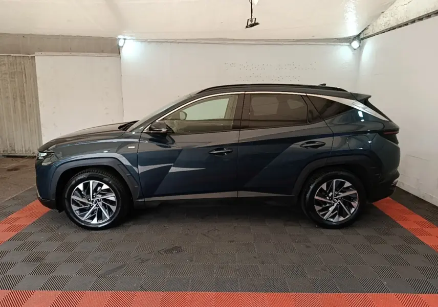 Vue de profil côté gauche du Hyundai Tucson bleu 2021 avec jantes alliage et vitres teintées dans un garage.