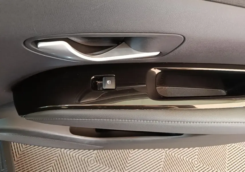 Gros plan sur la poignée intérieure et le bouton de verrouillage de la porte côté conducteur du Hyundai Tucson bleu 2021.