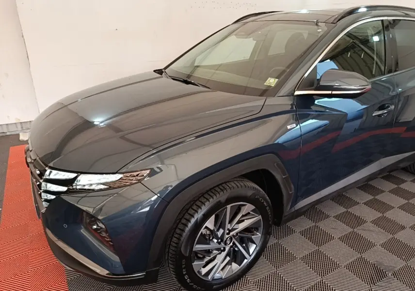 Vue 3/4 avant droit du Hyundai Tucson bleu avec jantes alliage et phares LED distinctifs.