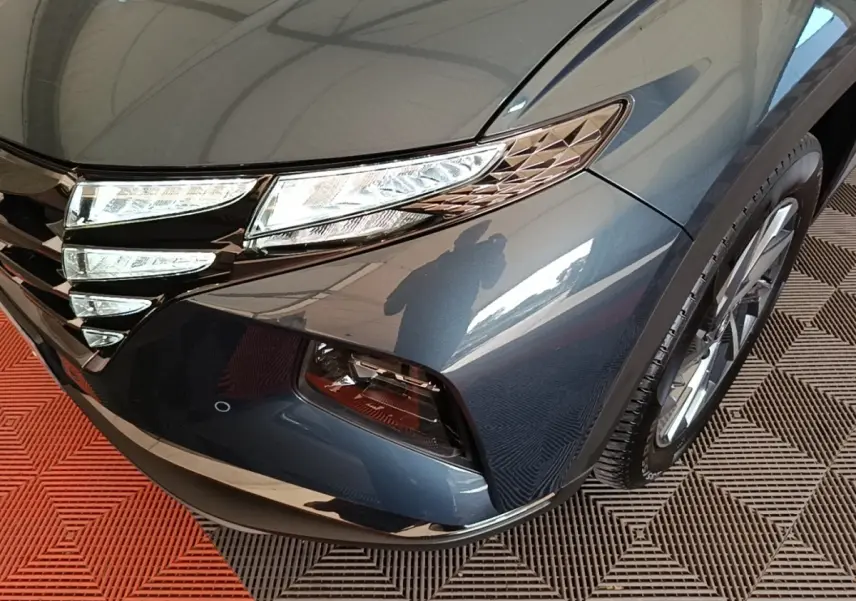 Gros plan sur l'avant droit bleu du Hyundai Tucson 2021, mettant en valeur les phares LED et la calandre distinctive.