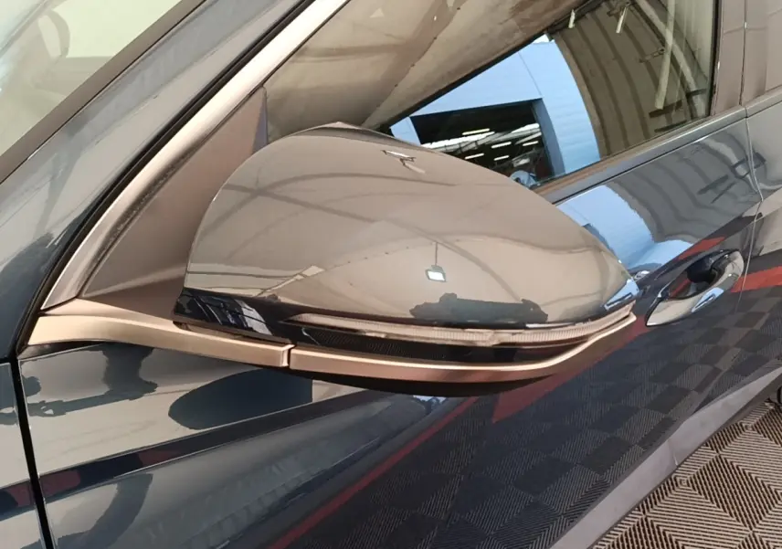 Rétroviseur côté conducteur bleu du Hyundai Tucson 2021 avec clignotant intégré et poignée de porte visible.