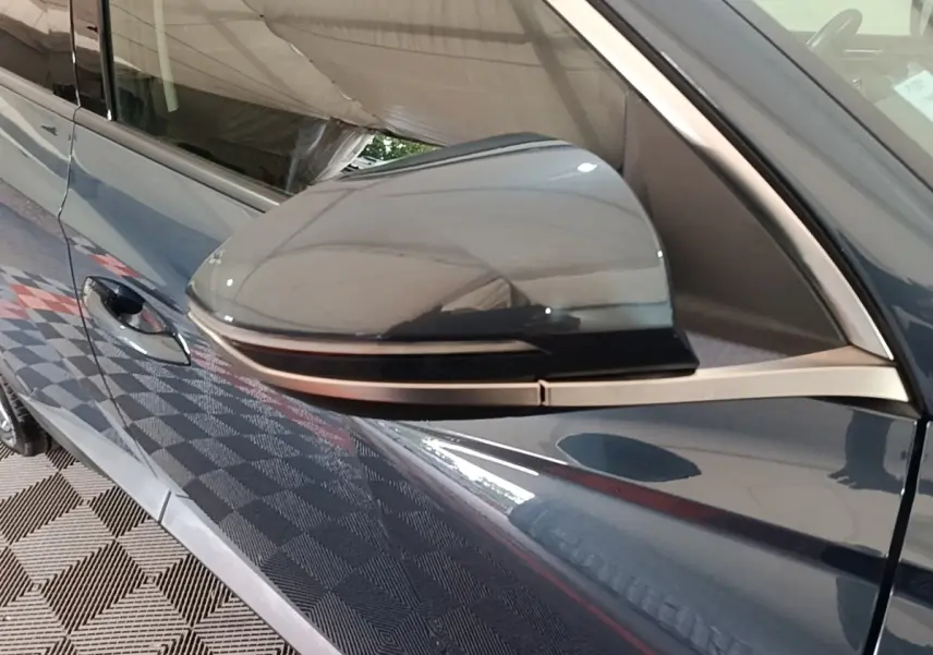 Rétroviseur côté conducteur du Hyundai Tucson bleu 2021, vue rapprochée sur la portière et poignée.
