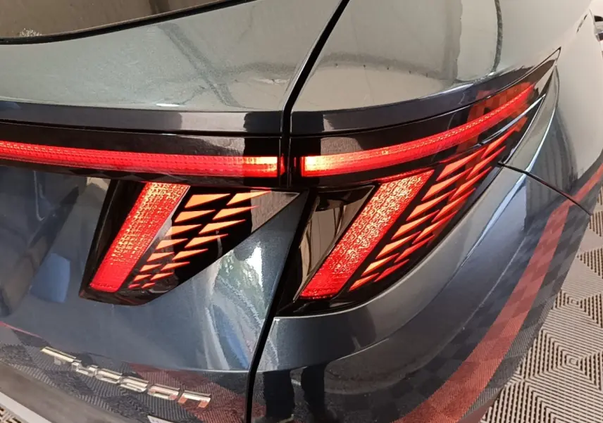 Gros plan sur le feu arrière droit rouge et la carrosserie bleue métallisée d’un Hyundai Tucson 2021.