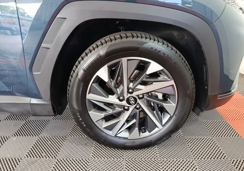 Gros plan sur la roue avant gauche bleu métallisé du Hyundai Tucson 2021 avec jante alliage au design moderne.