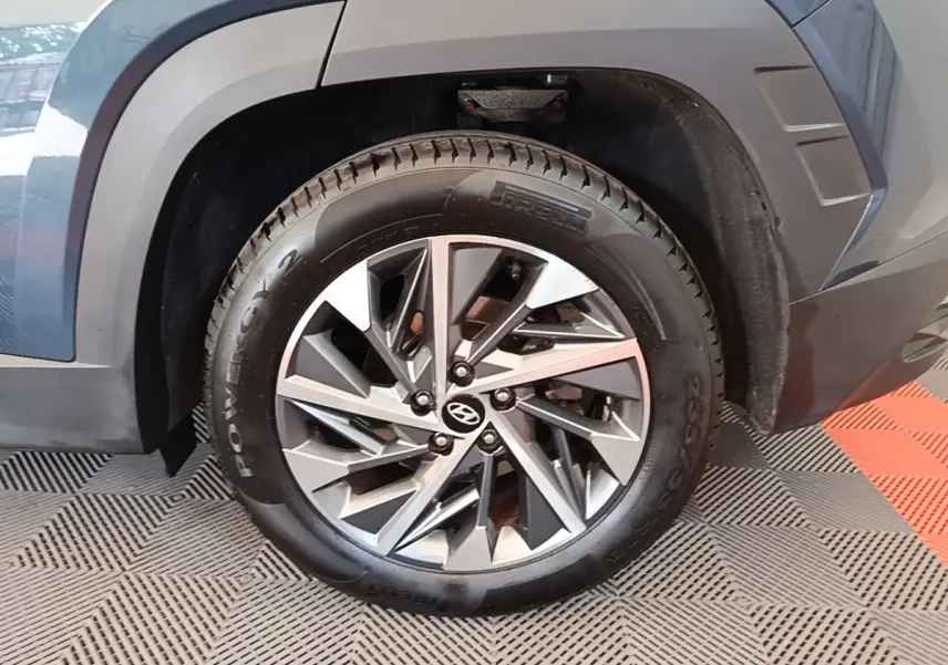 Gros plan sur la roue avant droite d’un Hyundai Tucson bleu avec jante alliage moderne et pneu Pirelli.