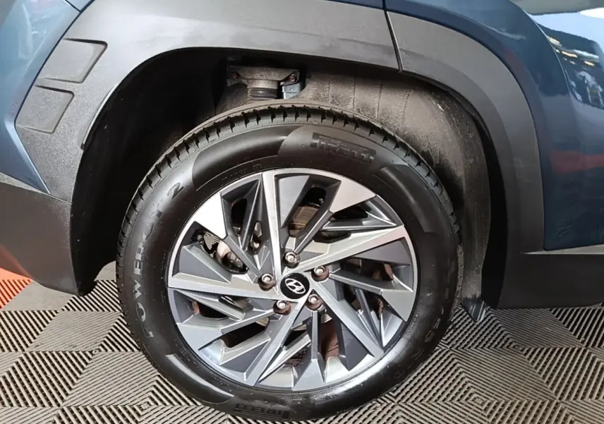 Gros plan sur la roue avant gauche d’un Hyundai Tucson bleu, avec jante alliage et pneu Pirelli Powergy.