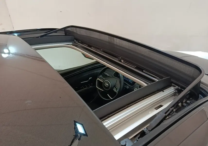 Vue plongeante sur l'intérieur d'un Hyundai Tucson bleu avec toit ouvrant panoramique ouvert.