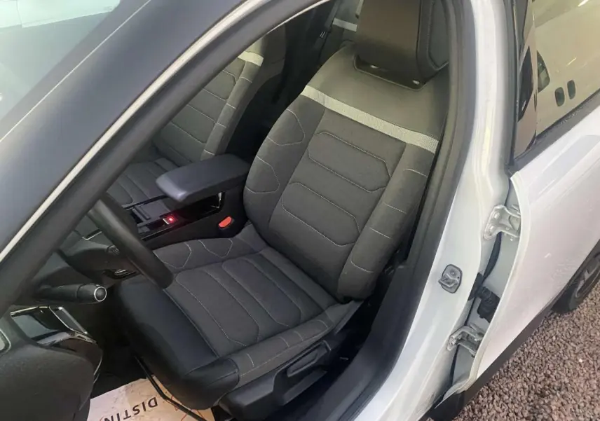 Vue intérieure côté conducteur d'une Citroën C4 blanche 2021, siège tissu gris avec accoudoir central ouvert.