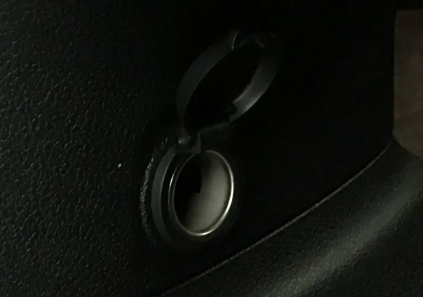 Gros plan sur la prise 12V noire ouverte dans l'habitacle du Peugeot Partner blanc, version 2025.