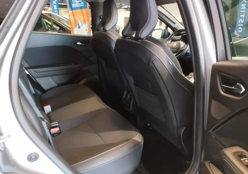 Vue intérieure côté arrière droit du Renault Symbioz gris Cassiopée, montrant les sièges arrière et l'avant du véhicule.