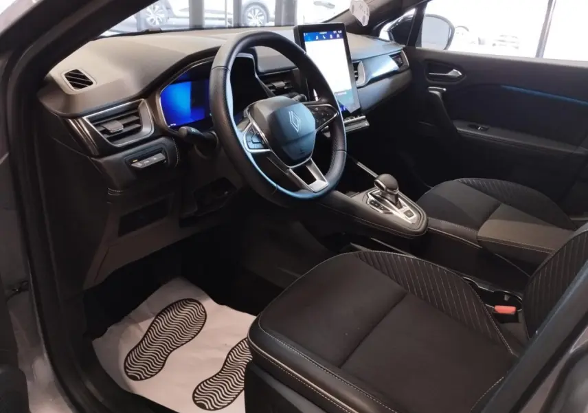 Vue intérieure côté conducteur du Renault Symbioz 2025, montrant le volant, écran tactile vertical et sièges noirs.