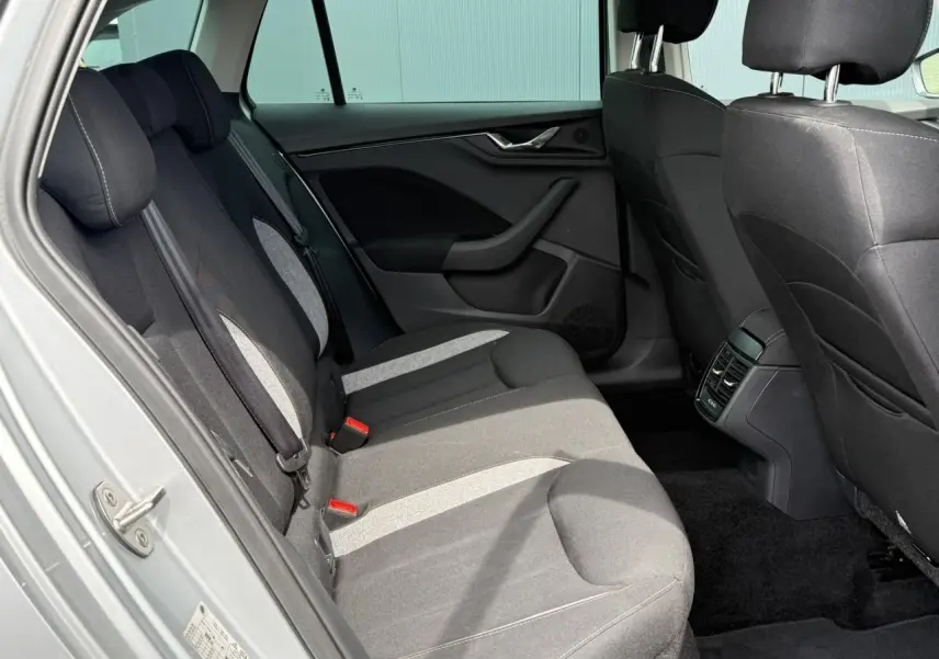 Vue intérieure côté arrière gauche de la Skoda Scala TSI 116 DSG7 Sélection, sièges tissu gris et noir.