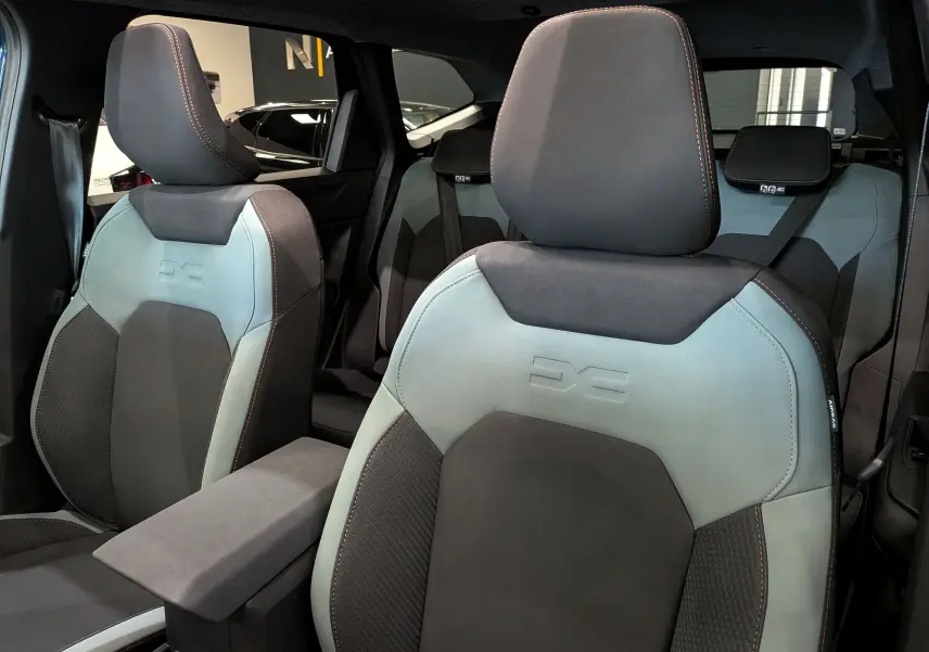 Gros plan sur les sièges avant en tissu bicolore gris et noir du Dacia Bigster 2026, avec logo embossé sur les dossiers.