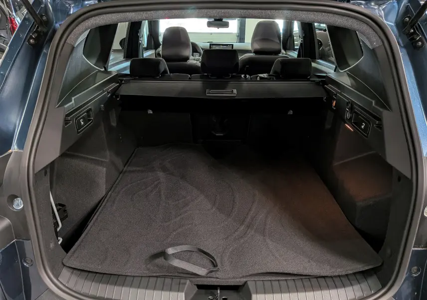 Vue arrière du coffre spacieux du Dacia Bigster Bleu Indigo, avec banquette arrière et cache-bagages visibles.