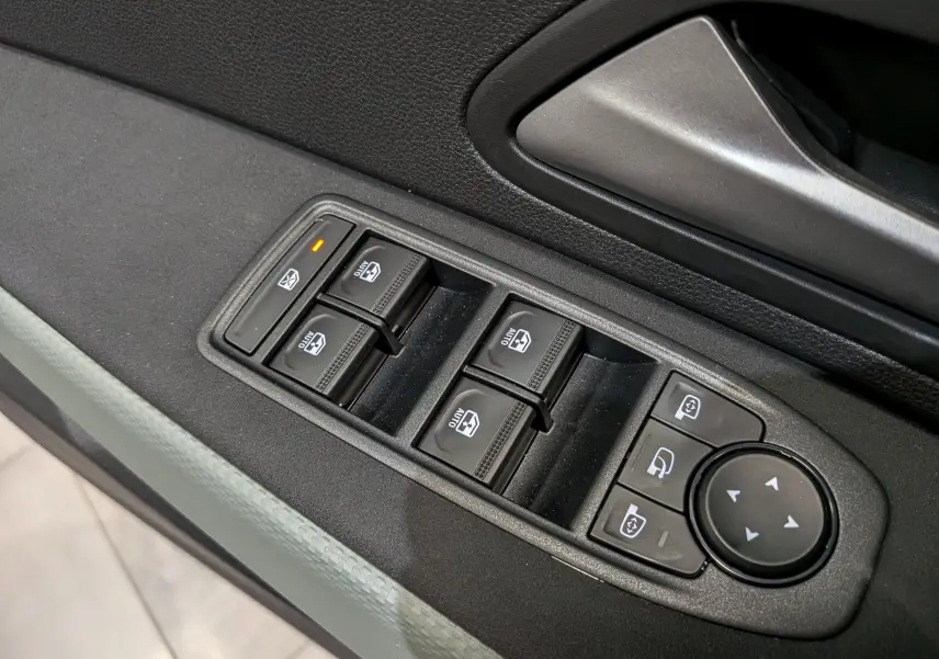 Gros plan sur les commandes de lève-vitres et rétroviseurs côté conducteur du Dacia Bigster bleu indigo.