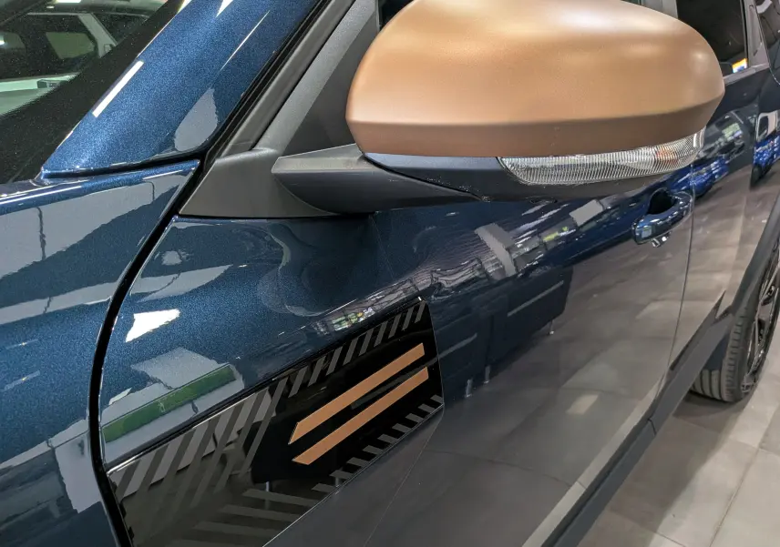 Gros plan sur le rétroviseur couleur bronze et la portière bleu indigo côté gauche du Dacia Bigster 2026.