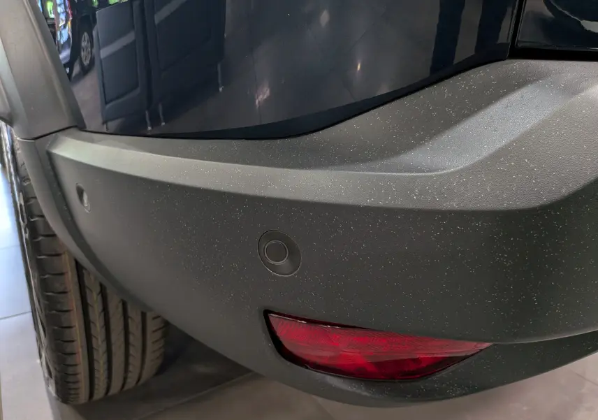Gros plan sur le pare-chocs arrière droit bleu indigo du Dacia Bigster avec feu antibrouillard et capteurs de stationnement.