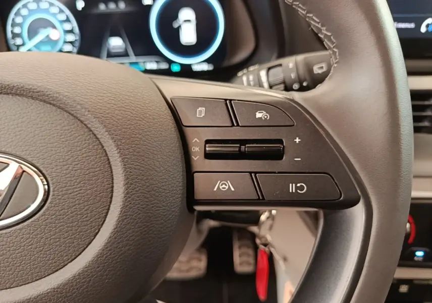 Gros plan sur le volant cuir gris du Hyundai Bayon 2024, avec commandes multifonctions et tableau de bord numérique en arrière-plan.