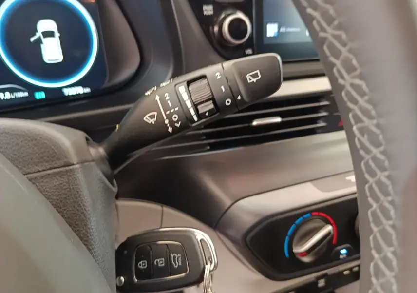 Gros plan sur la commande d’essuie-glace et le tableau de bord noir du Hyundai Bayon blanc, version hybride 2024.