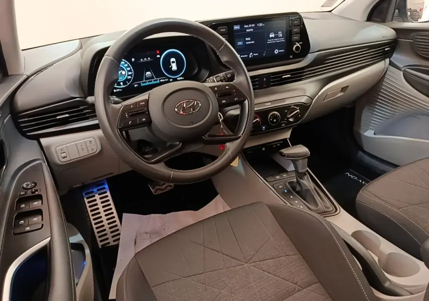 Vue intérieure avant du Hyundai Bayon blanc 2024, volant cuir multifonctions et écran tactile central visible.