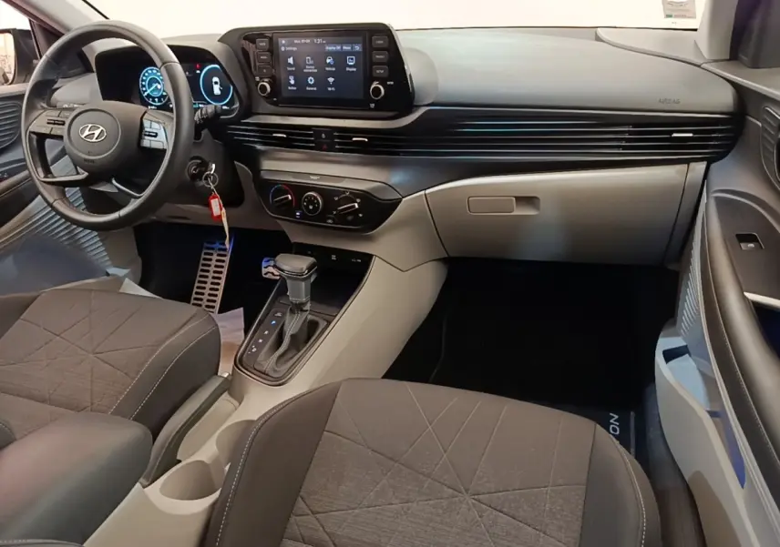 Vue intérieure avant droite du Hyundai Bayon 2024 avec tableau de bord noir et gris, écran tactile central et volant multifonctions.