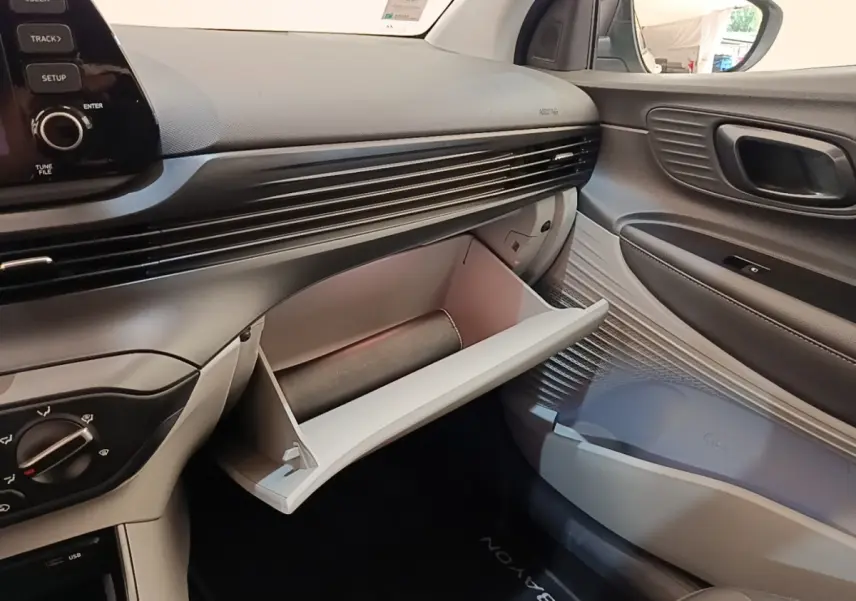Intérieur côté passager de la Hyundai Bayon 2024, boîte à gants ouverte et tableau de bord noir et gris.
