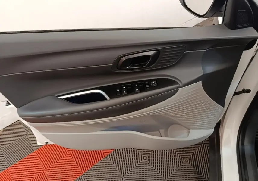 Vue intérieure de la porte avant gauche blanche du Hyundai Bayon 2024, avec commandes électriques et habillage bicolore gris et noir.