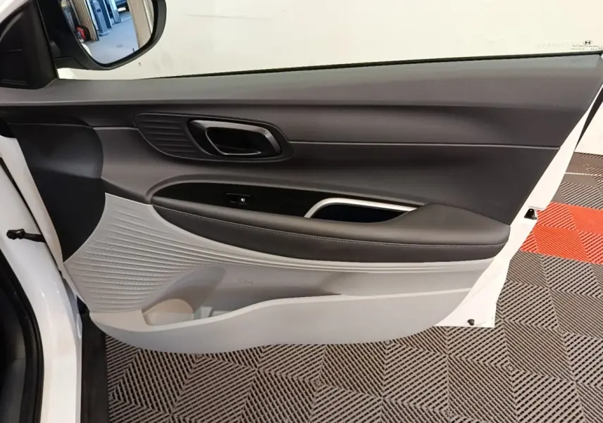 Vue intérieure de la porte avant gauche blanche du Hyundai Bayon 2024 avec garniture bicolore noire et grise.