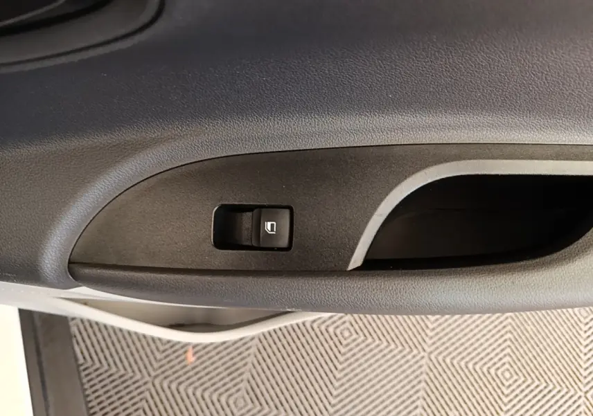 Gros plan sur la commande de lève-vitre côté conducteur d’une Hyundai Bayon blanche, intérieur noir.